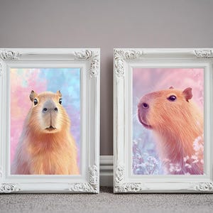 May include: Two framed art prints featuring capybaras. One print shows a capybara facing forward against a colorful background. The other print shows a capybara in profile with a soft pink and blue background. Both are in white ornate frames.