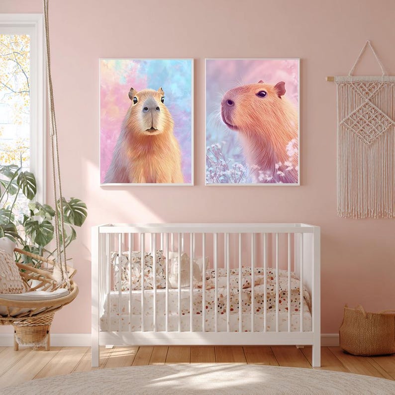 May include: Two framed art prints featuring capybaras. One print shows a capybara facing forward against a pastel background of pink, blue, and yellow. The other print shows a capybara in profile against a similar background. The prints are above a white crib.