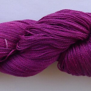 May include: A skein of deep purple yarn, with a subtle sheen. The yarn is soft and smooth, and would be perfect for knitting or crocheting.