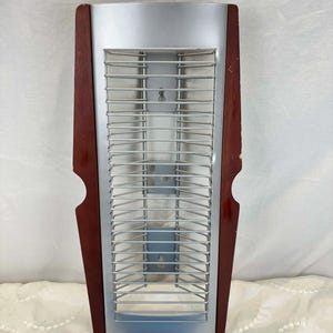 Peut inclure: Un radiateur électrique argenté et imitation bois avec une grille métallique. Le radiateur est de forme rectangulaire avec un dessus incurvé et est encadré de bois foncé sur les côtés. La marque "TECHPOINT" est visible en bas.