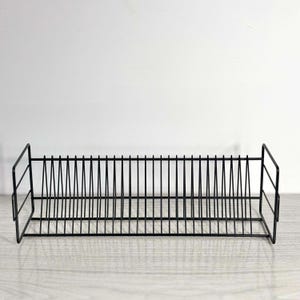 May include: A black metal record holder with vertical dividers. The holder is rectangular with a grid-like design, perfect for organizing vinyl records. The design is simple and modern, suitable for any home decor.