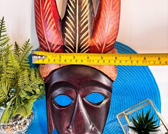 彫刻された木製の装飾的な壁マスク、羽根飾りが描かれた部族スタイル