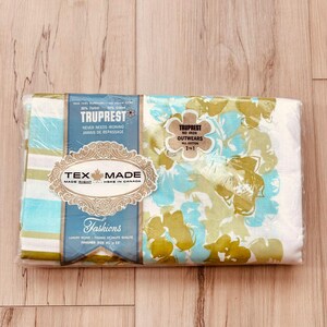 May include: A packaged vintage textile with a floral pattern in shades of blue, green, and white. The packaging includes labels with text such as "TRUPREST" and "TEX MADE". The finished size is 42 x 33 inches.