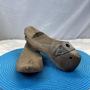Hormas de zapatos de madera antiguas con herrajes metálicos, pátina de taller vintage, auténtica decoración de zapatería industrial.