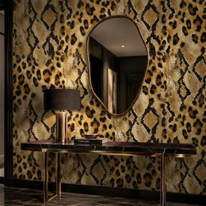 May include: A console table with a black marble top and gold metal legs, featuring a black lamp and a book titled Tom Ford. An irregular, organic-shaped mirror hangs on a wall covered in wallpaper with a combined leopard and snakeskin pattern.