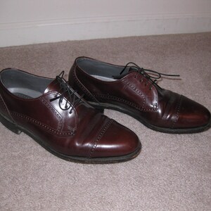 May include: A pair of brown leather oxford shoes with lace-up closures. The shoes have a wingtip design and a polished finish.
