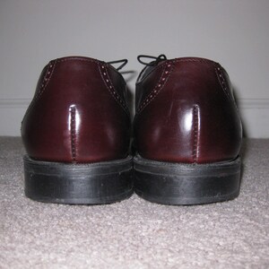 May include: A pair of burgundy leather dress shoes with lace-up closures. The shoes have a polished finish and a slightly pointed toe.