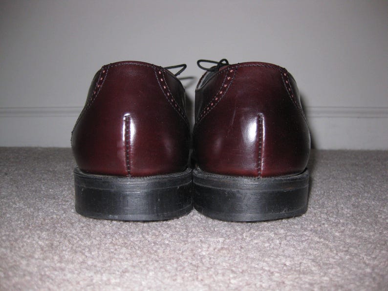 May include: A pair of burgundy leather dress shoes with lace-up closures. The shoes have a polished finish and a slightly pointed toe.