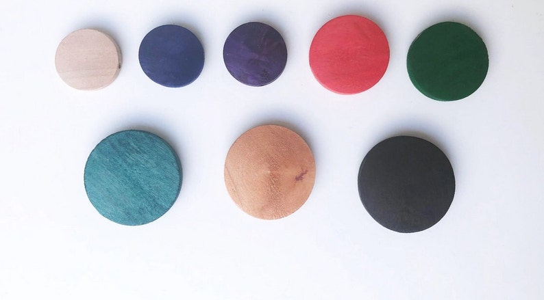 May include: Nine round wooden discs in various colors, including natural wood, dark blue, purple, red, dark green, light green, and black.