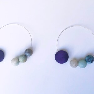 May include: Two silver wire necklaces with a purple wooden disc and a graduated set of three green and blue beads.