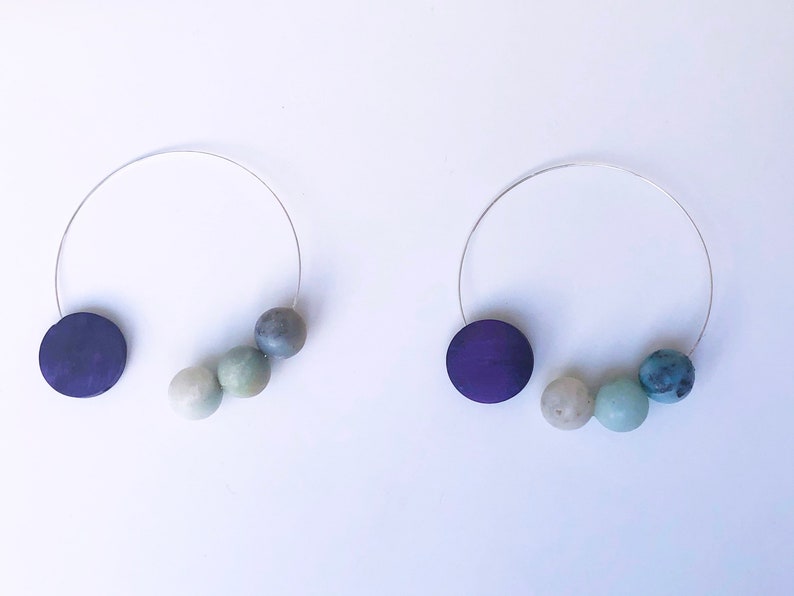 May include: Two silver wire necklaces with a purple wooden disc and a graduated set of three green and blue beads.