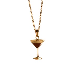 May include: Gold-toned necklace featuring a pendant shaped like a martini glass. The pendant has a dark brown interior, and the chain is delicate. The necklace is displayed against a white background.