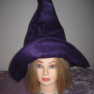 Pu&ograve; includere: Un cappello da strega viola con una corona alta e appuntita e un'ampia tesa. Il cappello &egrave; indossato da un manichino con lunghi capelli biondi.
