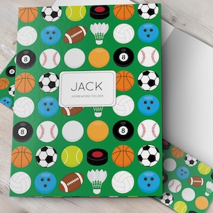 May include: A green homework folder featuring a repeating pattern of various sports balls and equipment, including basketballs, soccer balls, baseballs, and shuttlecocks. A central white rectangular label displays the text JACK HOMEWORK FOLDER.