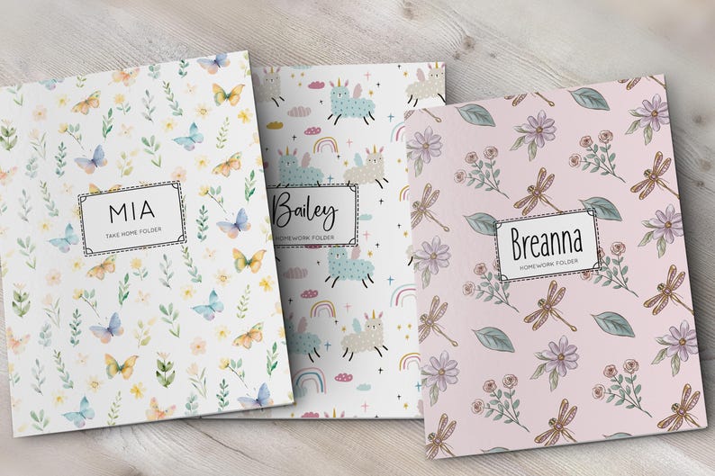 K&ouml;nnte beinhalten: Drei rechteckige Mappen mit personalisierten Etiketten. Die erste ist wei&szlig; mit Schmetterlingen und Blumen, beschriftet mit MIA TAKE HOME FOLDER. Die zweite ist wei&szlig; mit Einh&ouml;rnern und Regenb&ouml;gen, beschriftet mit Bailey HOMEWORK FOLDER. Die dritte ist rosa mit Libellen und Blumen, beschriftet mit Breanna HOMEWORK FOLDER.