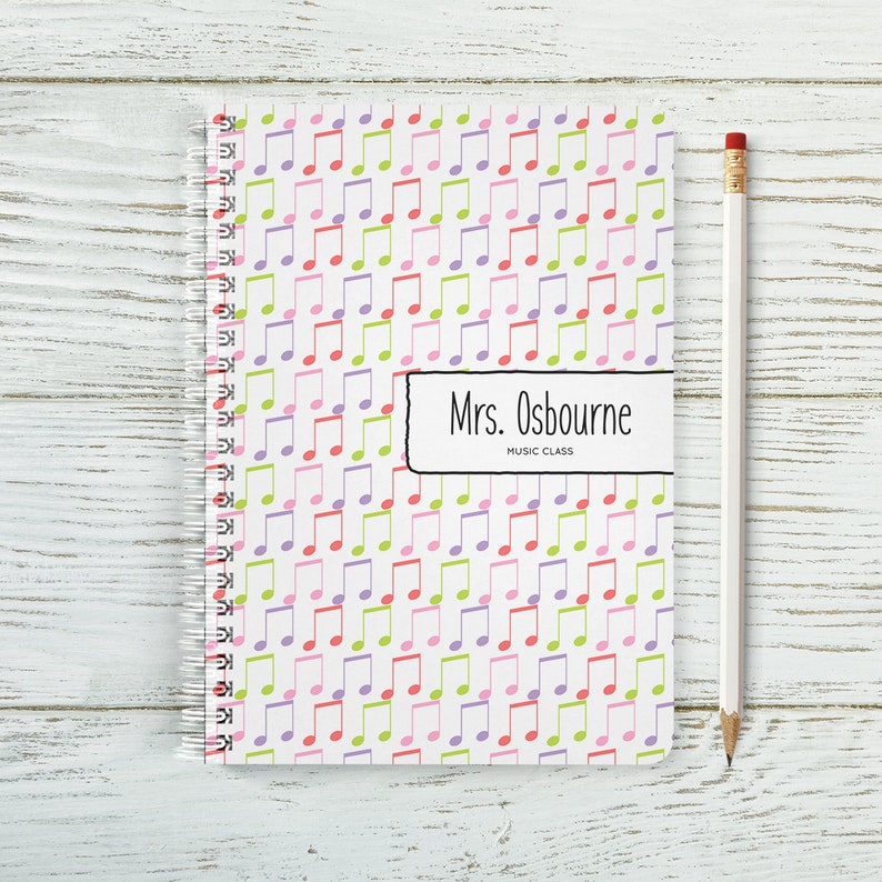 May include: A white spiral notebook with a colourful music note pattern. The notebook has a label that says "Mrs. Osbourne Music Class".