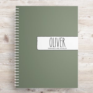 May include: A green spiral bound notebook with a white label that says "Oliver Drawings and Doodles".