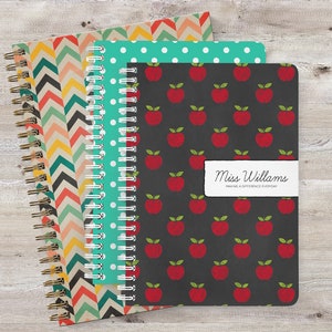 May include: Three spiral bound notebooks with different patterns. The first notebook has a chevron pattern in shades of orange, yellow, and blue. The second notebook has a white polka dot pattern on a teal background. The third notebook has a red apple pattern on a black background. The third notebook has a label that reads "Miss Williams Making a Difference Everyday".
