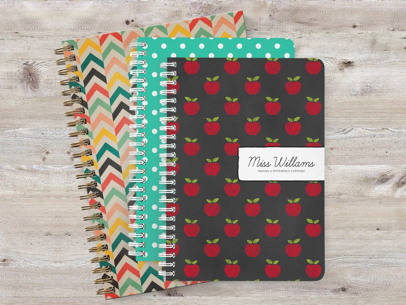 May include: Three spiral bound notebooks with different patterns. The first notebook has a chevron pattern in shades of orange, yellow, and blue. The second notebook has a white polka dot pattern on a teal background. The third notebook has a red apple pattern on a black background. The third notebook has a label that reads "Miss Williams Making a Difference Everyday".