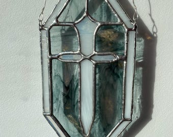 May include: A stained glass window featuring a white cross in a diamond-shaped frame with a green background.