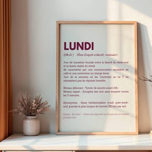 May include: A framed print with a white background and a burgundy text overlay. The text reads "LUNDI" in a large font, followed by a definition of the word in French. The definition includes the word "LUNDI" and describes the day as a "collective state of mind, dreaded".