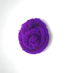 May include: A purple, crocheted flower with a textured, swirl design.