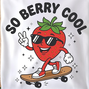 May include: White t-shirt featuring a cartoon strawberry wearing sunglasses and riding a skateboard. The text "SO BERRY COOL" is above the strawberry. The strawberry is red with a green stem and is giving a peace sign.
