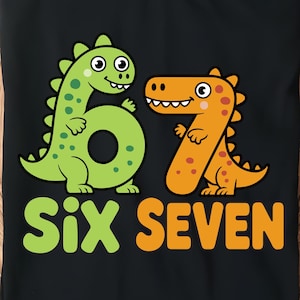 Pode incluir: Camiseta preta com um dinossauro verde formando o número 6 e um dinossauro laranja formando o número 7. As palavras "Six SEVEN" são impressas em laranja abaixo. A camiseta é exibida em uma bandeja de madeira.