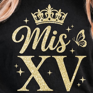 May include: Black t-shirt with gold glitter text and graphics. The design includes the words "Mis XV" with a crown, butterfly, and stars. The shirt is a crew neck and has rolled-up sleeves.
