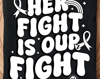 Puede incluir: Camiseta negra con el texto blanco "HER FIGHT IS OUR FIGHT", con un lazo, arcoíris, nubes y estrellas. La camiseta se muestra en una bandeja de madera con decoraciones festivas.