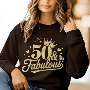 May include: A black sweatshirt with gold glitter lettering that says "50 & Fabulous" with a crown above the 50.