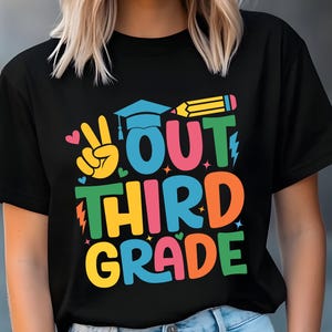 Könnte beinhalten: Schwarzes T-Shirt mit einer bunten Grafik, auf der "Out Third Grade" mit einer Abschluss-Kappe, einem Bleistift, einem Peace-Zeichen und Herzen steht.
