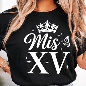 May include: Black t-shirt with the text "Mis XV" in white script, a crown, a butterfly, and the Roman numerals XV. The design includes star accents.