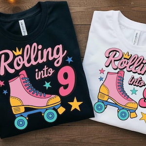 Puede incluir: Dos camisetas, una negra y otra blanca, con el texto "Rolling into 9". Cada camiseta presenta un diseño de patín de ruedas rosa con detalles amarillos y azules, junto con estrellas y una corona.