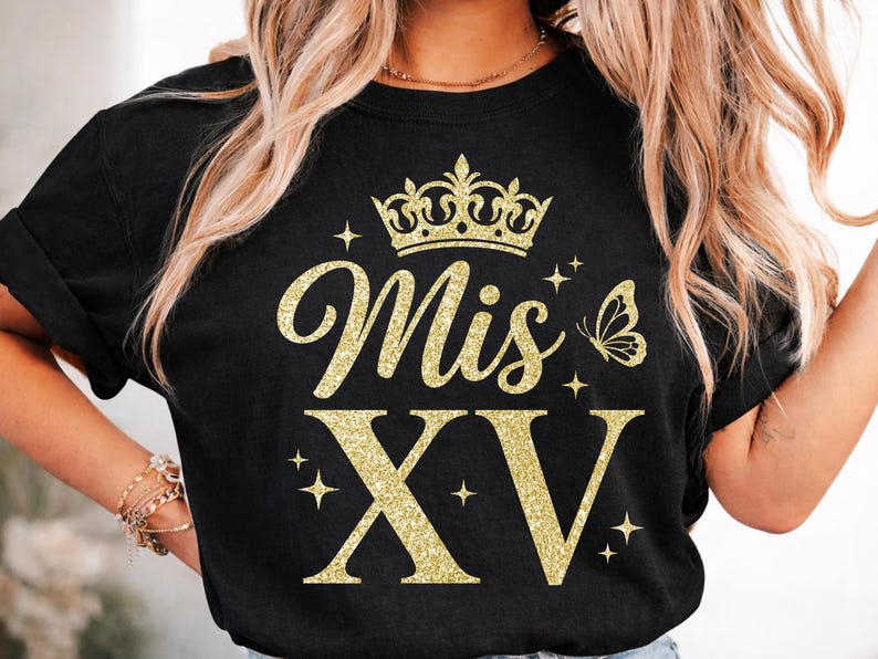 May include: Black t-shirt with gold glitter text and graphics. The design includes the words "Mis XV" with a crown, butterfly, and stars. The shirt is a crew neck and has rolled-up sleeves.