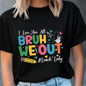 May include: Black t-shirt with a colorful graphic that reads "I Love You All BRUH WE OUT #Lunch Lady". The design includes a pencil, paper airplane, peace sign, and hearts.