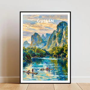 以下が含まれることがあります： 中国の桂林の風景を描いた額装アートプリント。そびえ立つカルスト山脈、緑豊かな植生、小舟が浮かぶ川が特徴です。空は暖かい夕日の色合いで描かれ、上部中央にGUILIN CHINAというテキストが配置されています。