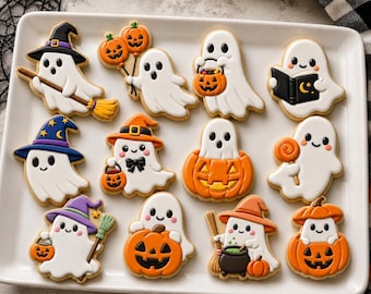 May include: A collection of twelve Halloween-themed sugar cookies arranged on a white rectangular platter. The cookies are shaped like white ghosts, orange pumpkins, and ghosts interacting with items like brooms, books, and jack-o'-lantern buckets.