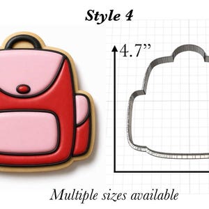 Op de afbeelding: Een rugzakvormig koekje met rode en roze glazuur naast een metalen uitsteekvorm. De vorm is 11,9 cm hoog en 12,7 cm breed. De tekst Style 4 staat bovenaan en Multiple sizes available staat onderaan de afbeelding vermeld.