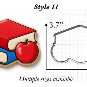 Op de afbeelding: Een koekjesvorm in de vorm van een stapel van twee boeken met een appel, gelabeld Style 11. De metalen omtrek toont een hoogte van 3,7 inch en een breedte van 5,0 inch op een rasterachtergrond, wat de fysieke afmetingen aangeeft.