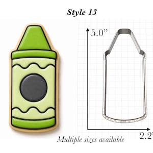 Op de afbeelding: Een lichtgroen koekje in de vorm van een waskrijtje met zwarte omlijningen en een donkergrijze cirkel in het midden, naast een metalen uitsteekvormpje in dezelfde vorm. De afbeelding bevat de tekst Style 13 en afmetingen van 12,7 cm bij 5,6 cm.
