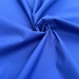 May include: A close-up shot of a vibrant blue fabric with soft folds and subtle textures. The material appears smooth and possibly water-resistant, ideal for clothing or crafting projects. The color is a rich, saturated blue.