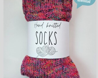 Op de afbeelding: Handgebreide sokken in een levendige mix van roze, paarse en teal garens. De sokken zijn verpakt met een witte band met de tekst "Hand knitted SOCKS" met een illustratie van een bol garen. Een tekstballon zegt "digitaler download".
