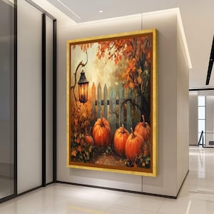 May include: A framed painting shows an autumnal scene with pumpkins, a wooden fence, and a lantern. The pumpkins are orange, and the leaves are shades of orange and brown. The painting is in a gold frame and hangs on a white wall.
