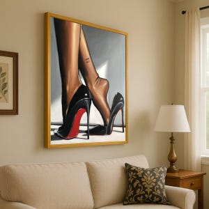 May include: A framed artwork depicting legs in black high-heeled shoes with red soles. The artwork is in a gold frame and hangs on a beige wall. The tattoo on the leg reads "Why Not".
