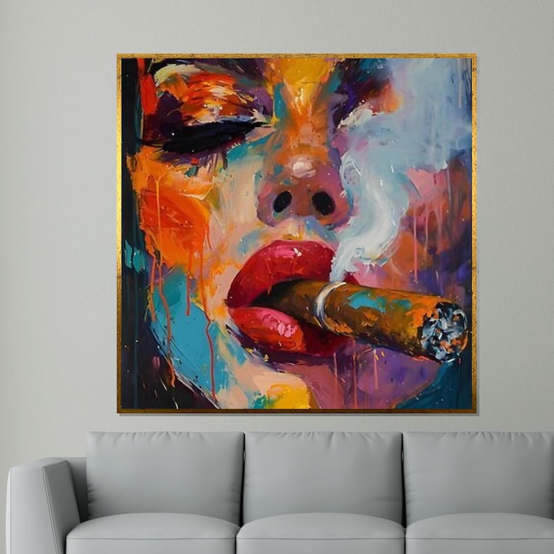 May include: Abstract painting of a person smoking a cigar. The artwork features vibrant colors, including red lips, orange, blue, and purple hues. The painting is framed with a gold border and depicts smoke rising from the cigar.