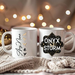 K&ouml;nnte beinhalten: Zwei wei&szlig;e Keramikbecher. Ein Becher zeigt ein schwarzes und goldenes Design mit dem Text "ONYX STORM" und der andere Becher hat ein goldenes Design mit f&uuml;nf Drachen und dem Text "Any Name".