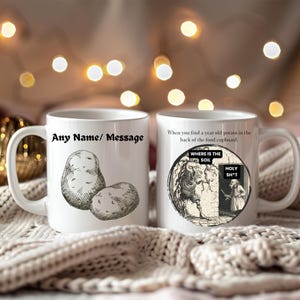 Pode incluir: Caneca de cerâmica branca com alça. Apresenta uma ilustração de batata e o texto "Any Name/ Message". O outro lado tem uma ilustração vintage e o texto "When you find a year old potato in the back of the food cupboard."