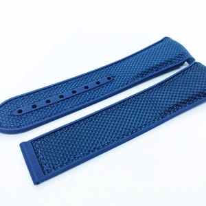 May include: A pair of new, blue watch straps. The straps are made of a textured material with a grid pattern. One strap has several holes for adjustment, and the other has a buckle. The straps are a deep, solid blue color.