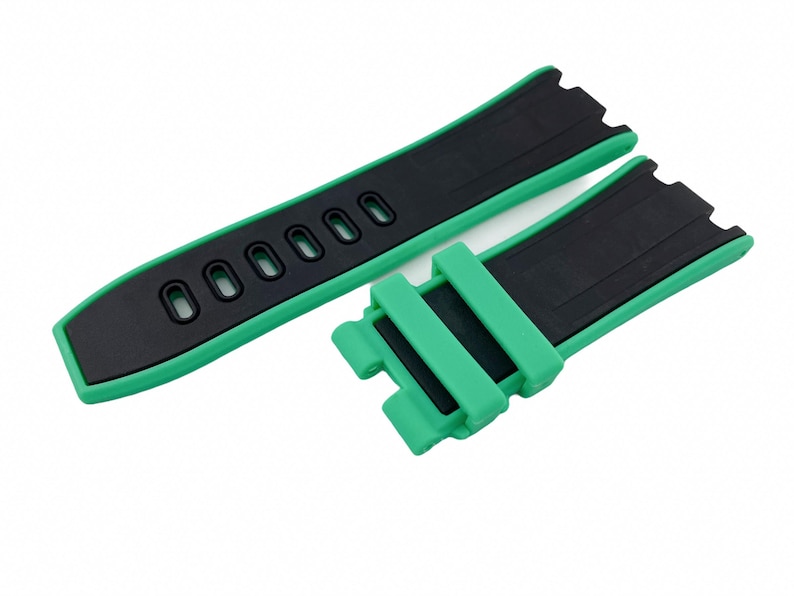May include: A green and black watch strap with a buckle. The strap has a textured surface and is made of silicone.